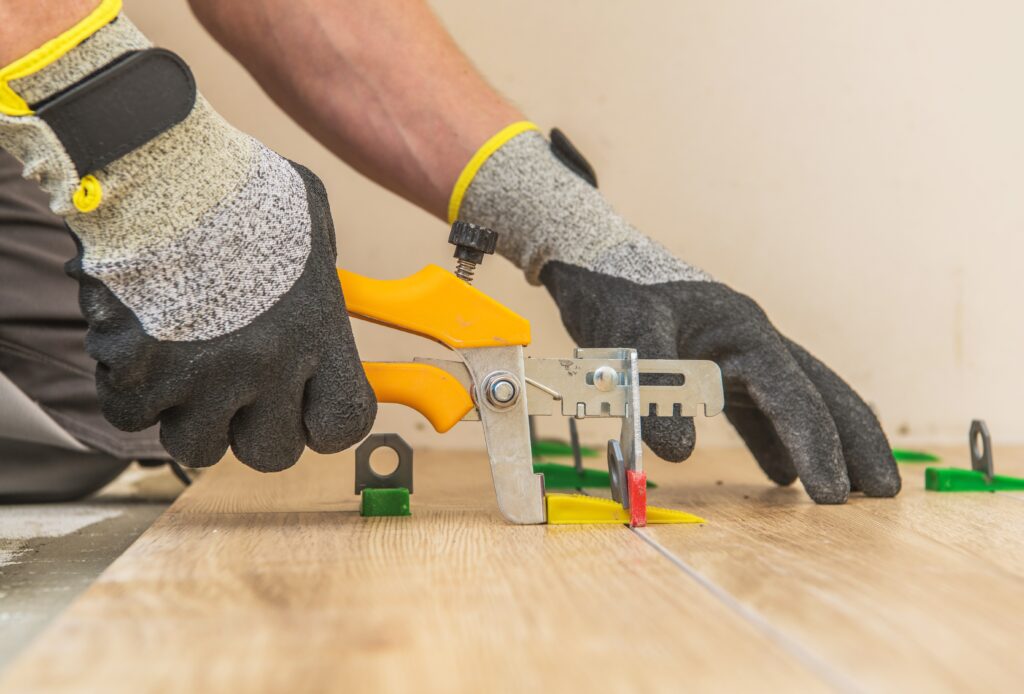 Ceramic Tiles Leveling System. Worker Installing Leveling Separators Between Floor Tiles.